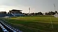 Pohled z jižního rohu stadionu na hlavní tribunu (červenec 2018)
