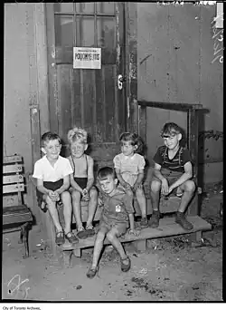 Stanley Barracks, kids on step, with polio sign on door
