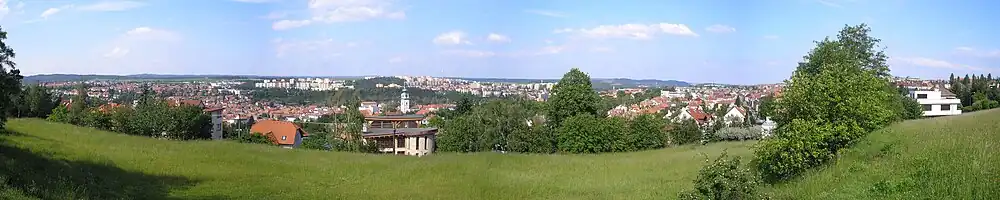 Pohled na severní žulosyenitovou rovinatou část Třebíče ze Strážné hory; v pozadí jsou patrné rozsáhlé lesy a sídliště vybudovaná na podkladu, ze kterého se uvolňuje problémový radon.