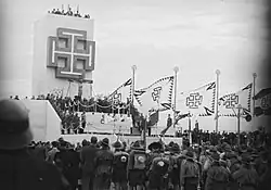 Tribuna Vlastenecké fronty během velkého apelu ve Vídni na bývalém vojenském cvičišti na Schmelzu v 15. okrese 18. října 1936, v popředí snímku v uniformách nově založená fronta rakouské vlastenecké mládeže „VF-Werk Österreichisches Jungvolk” (ÖJV)