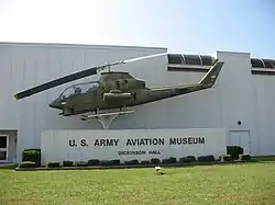 Bitevní vrtulník Bell AH-1 Cobra vystavený před vchodem