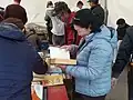 Čtenářka listující knihou během knižního veletrhu