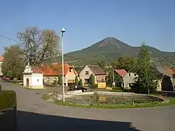 Náves ve Vchynicích od jihovýchodu, v pozadí vrch Lovoš.