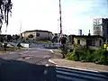 Železniční přejezd se závorami na trati z Prahy do Rakovníka, stavba metra, stanice Nádraží Veleslavín, v pozadí vlevo budova základní školy v nových Vokovicích