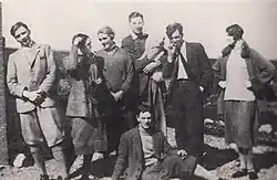 Richard Plunket Greene, první zleva, Olivia Plunket Greene, druhá zleva, David Plunket Greene, držící psa, Terence Greenidge, kouřící, druhý zprava, Elizabeth Frances Russell, první zprava, Evelyn Waugh, sedící