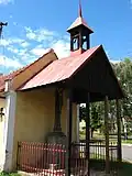 Hasičská zbrojnice, na jejíž zadní stěně je přistavěna zvonička a pod ní kříž s korpusem Krista