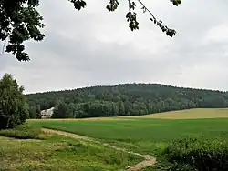 Vrch Vysoká u Jítravy. Na úpatí se nachází přírodní památka Bílé kameny