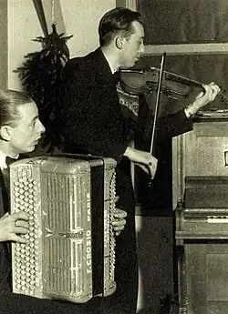 Westerbork, Nizozemsko, houslista a harmonikář hrající hudbu na štědrovečerní večeři