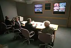 Prezident George W. Bush, náčelník štábu Bílého domu Andy Card (vlevo), Donald Richards (daleko vlevo) a admirál Richard Mies při videokonferenci na Offutt Air Force Base v Bellevue v Nebrasce. 11. září 2001