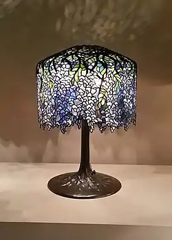 Barevná secesní stolní lampa s abažurem z barevných skleněných dílků spojených měděnou páskou, inspirovaným barvami a tvary květů vistárie