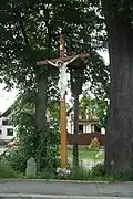 Dřevěný kříž, dřevěná zvonice a smírčí kámen stojící na návsi