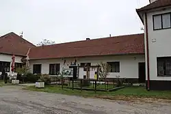 přízemní světle omítnutá budova s tmavě červenou střechou. U vchodu do objektu vlají dva prapory, jedním je slovenská vlajka, druhým vlajka Zemianského Podhradí. Před objektem se nachází oplocená zatravněná plocha se dvěma nástěnkami a informační tabulí.